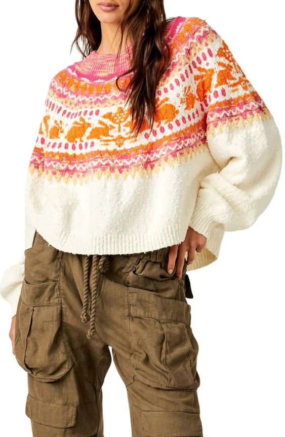 A Woman wearing army green cargo pants and ivory orange and pink fair isle sweater. 