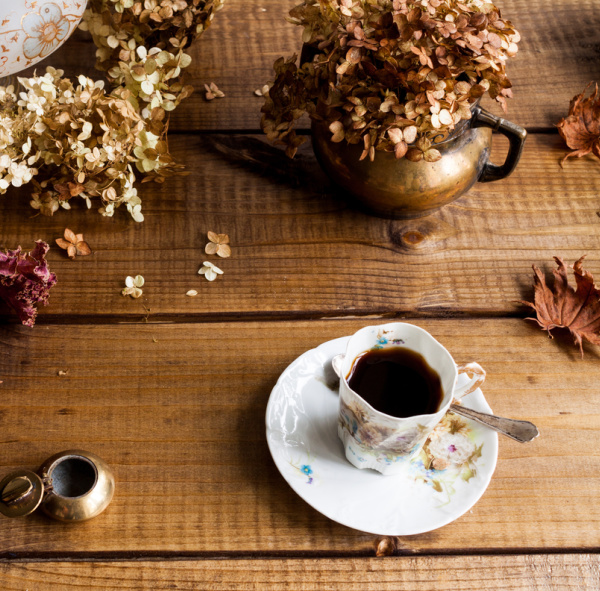 dried hydrangeas in a brass pot with a cup of coffee.