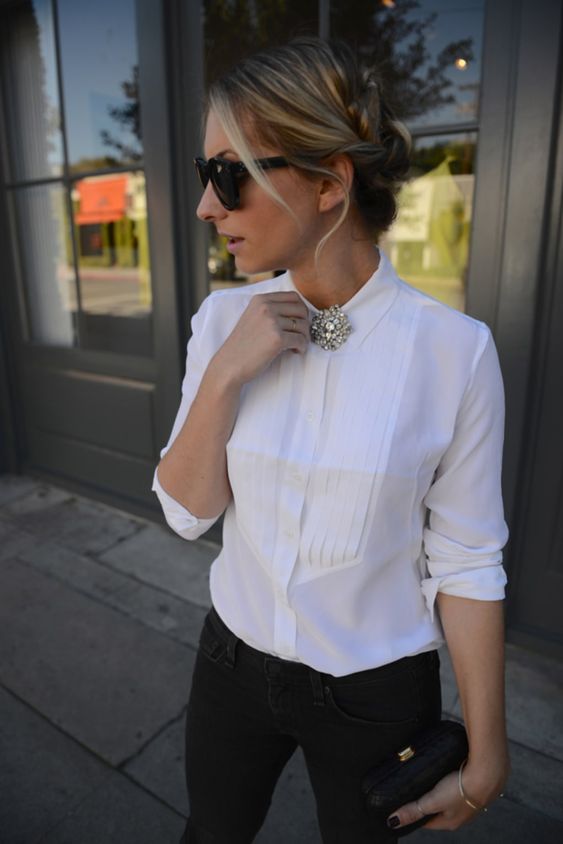 A woman wearing a white blouse with a brooch at the color. 