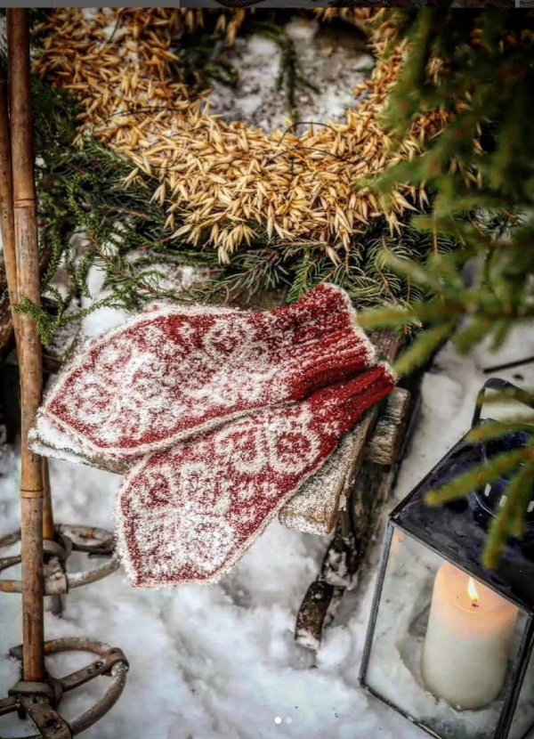 red mittens in the snow alongside a lantern