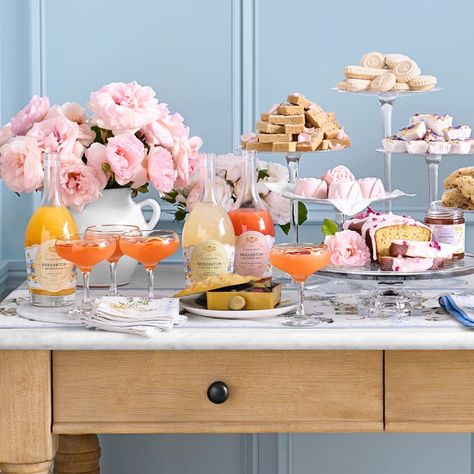 Bridgerton, A table filled with flowers, trays with cookies and scones and colorful drinks in pitchers. 