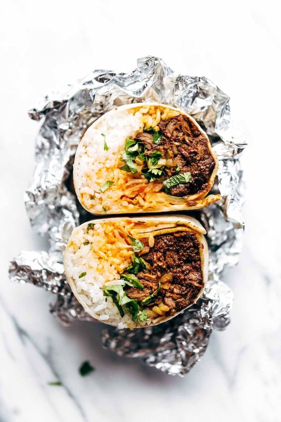 Korean bbq burrito cut in half wrapped in foil. 