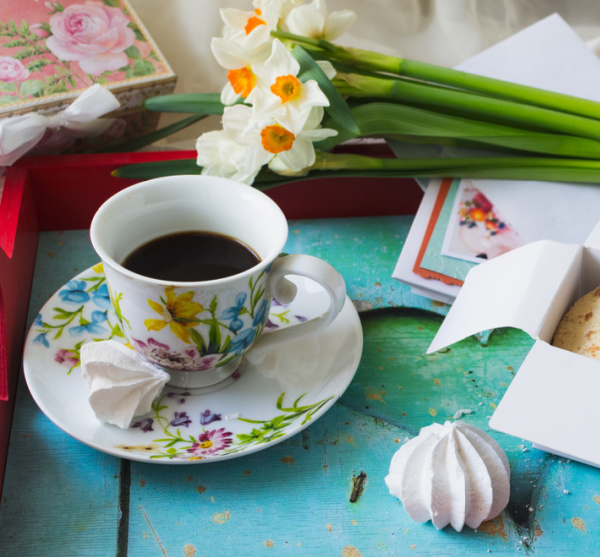 daffodils and a cup of coffee in a flower cup on a tray