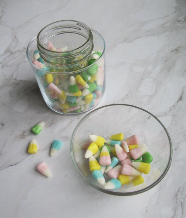 Easter flower centerpiece with a bowl of pastel easter candy corns and a jar willed with water and candy corns. 