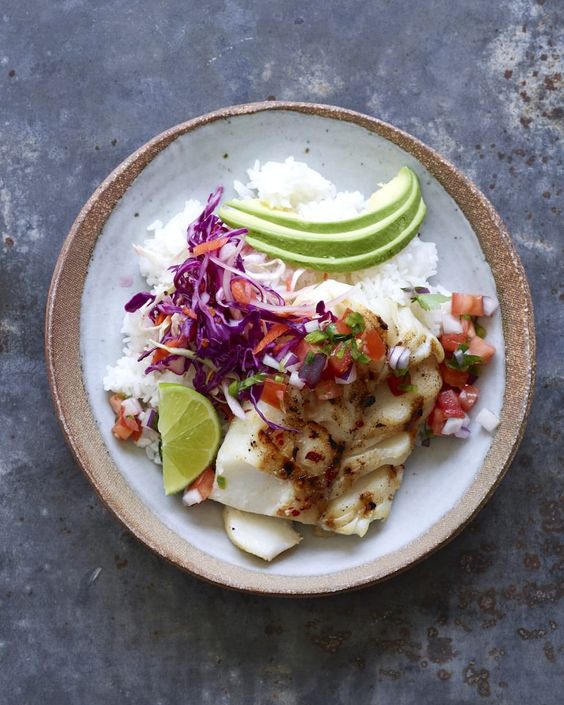 Gish taco bowls with white rice, fish, pickled onions, lime and avocado. 
