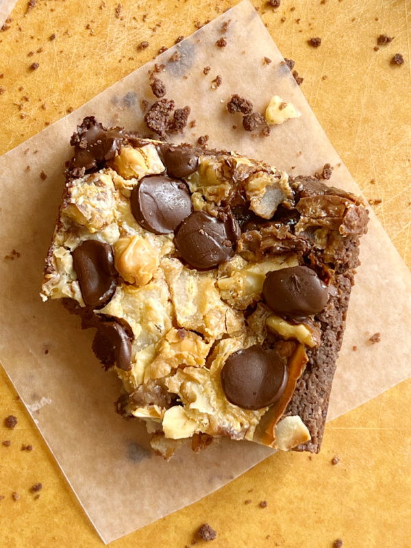 Seven Layer Brownie Bar with a bite taken out sitting on a piece of waxed paper. 