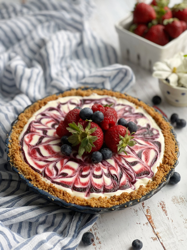 Patriotic Red White and Blue No-Bake Cheesecake with a basket of strawberries.
