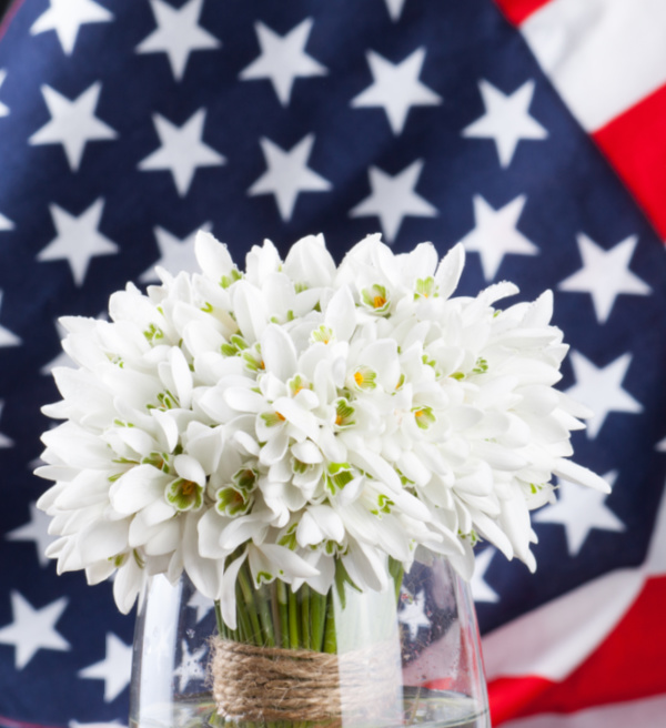 White flowers in a vase with an American flag in the background