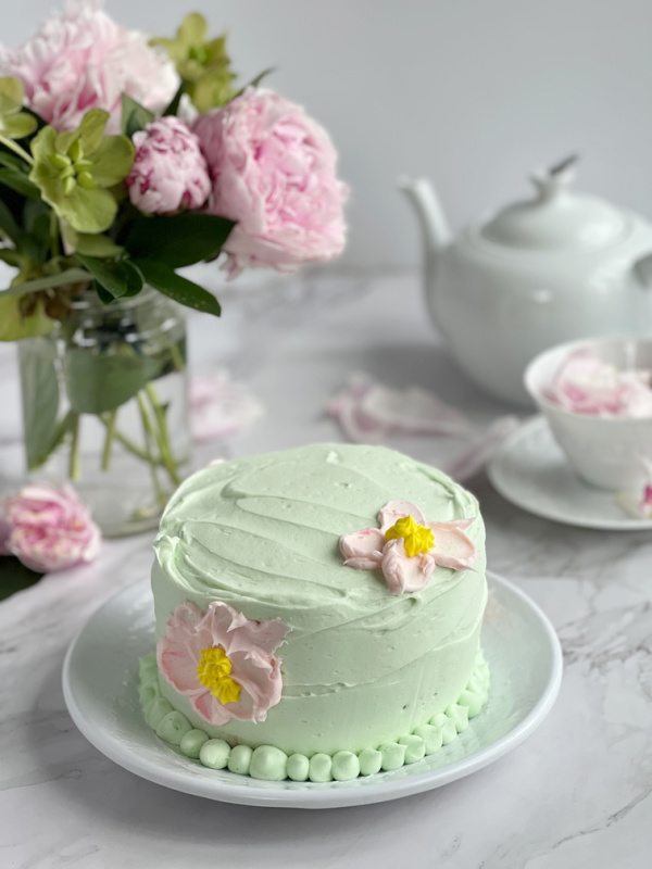 chocolate cake decorated with green buttercream frosting and pink flowers.