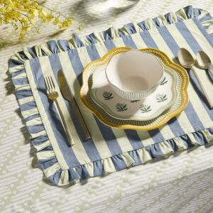 Rhode x West Elm blue and white stripe place mat, yellow plate, flower plate and a bowl with yellow flowers and silverware.