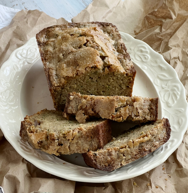 zucchini bread with crunchy sugar crust on a white platter.