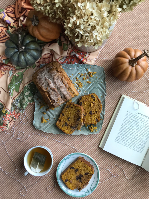 Autumn Spice Loaf Cake on a green pottery plate with a cup of tea and a book opened to chapter September.