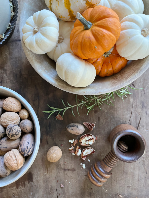 Fall flatlay Ironstone bowl of pumpkins and an ironstone bowl of pecans with a wood nutcracker