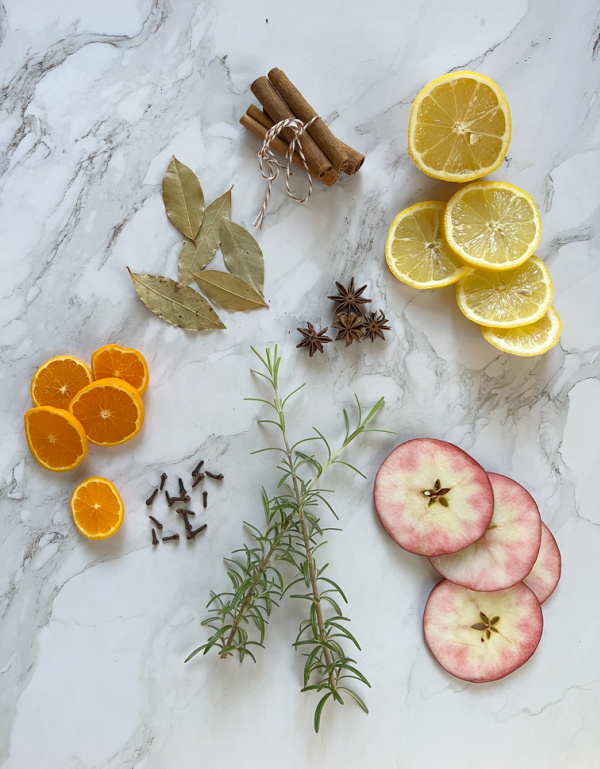 Fall simmer pot ingredients including lemons, ranges, apples, bay leaves, cloves, star Anise, rosemary, and cinnamon