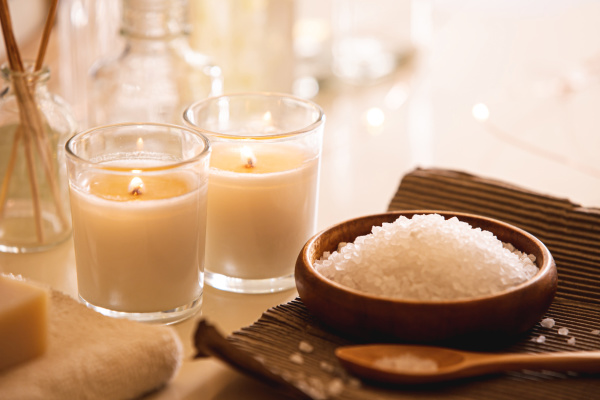 Fall self-care, a wood bowl of bath salts and two white candles. 