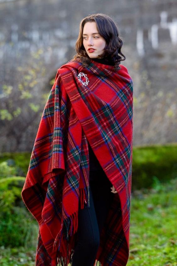 Woman wearing a tartan scarf with a pin on her shoulder. 