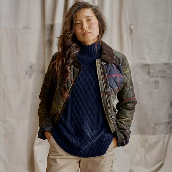 Woman wearing a blue sweater, tan pants and Orvis plaid Barn coat. 