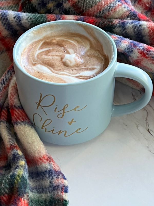 Intentional living after 50 morning ritual with Cup of hot chocolate on a plaid blanket.