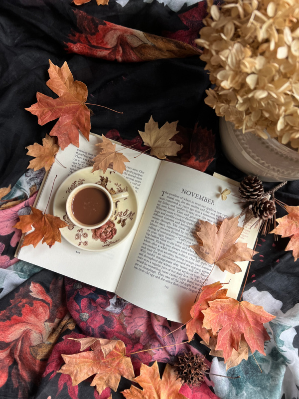 November flatlay with fall leaves, dried hydrangeas and a book opened to November.