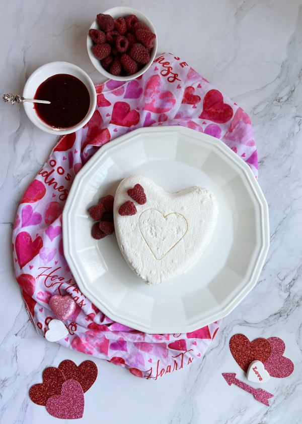 Coeur a La Creme With Raspberry Sauce on white plate with raspberries and small hearts.