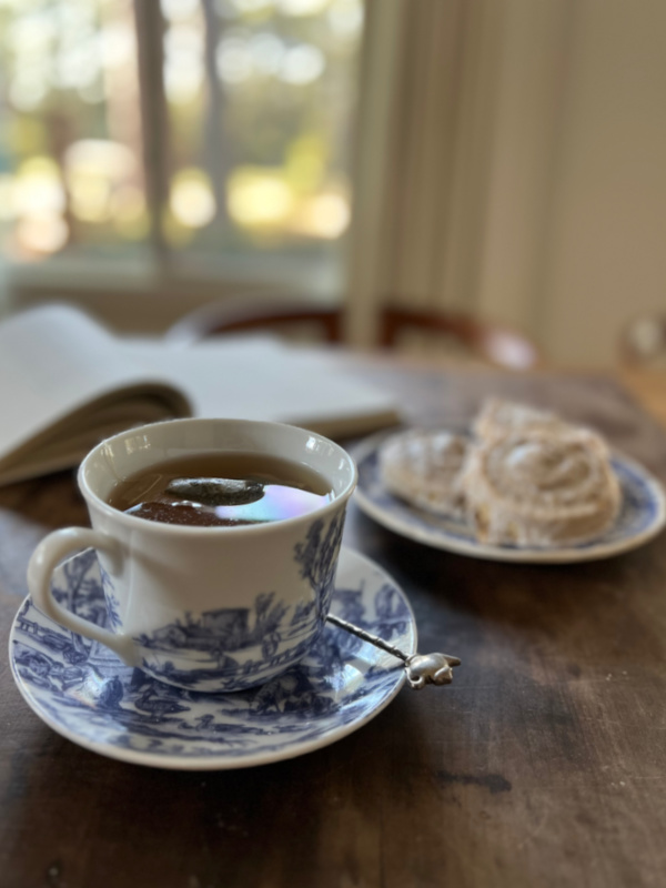 blue and white cup with tea and a snail danish.