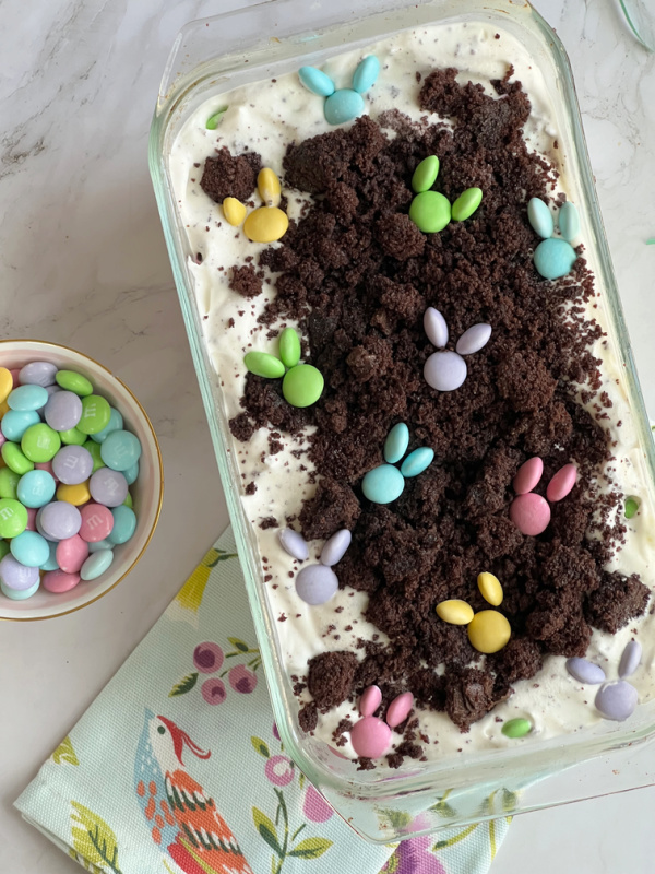 No Churn Easter M&M Ice Cream in a glass loaf pan with a bowl of pastel M&M candy. 