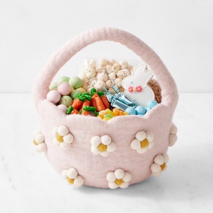 Pink felt easter basket with daisies filled with candy.