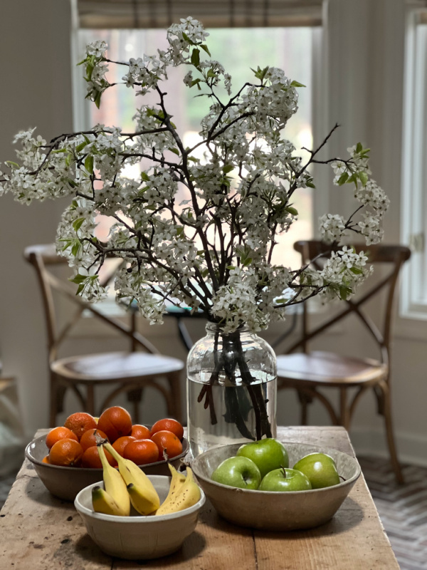 pear blossoms in a jar with 3 bowls of fruit