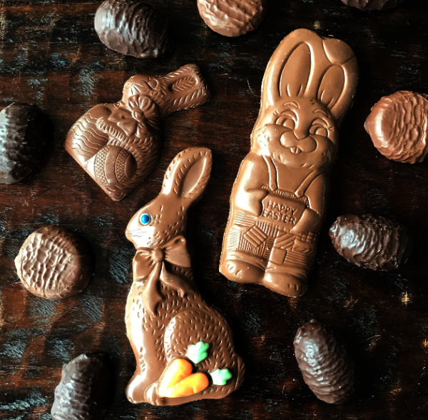 Three chocolate Easter rabbits surrounded by chocolate eggs.