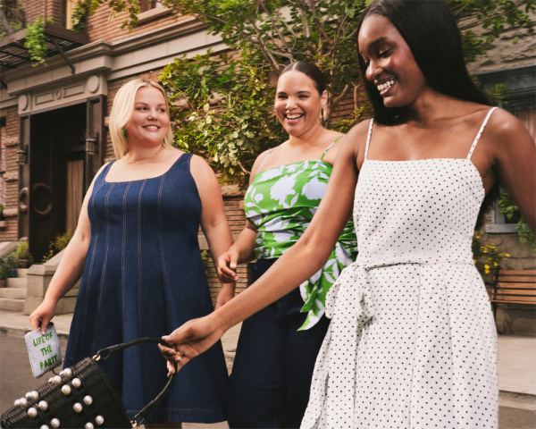 Three women, one in a blue dress, one in a green nd white dress and one in a white dress walking Dorn the street, kates pade newyork xT arget.