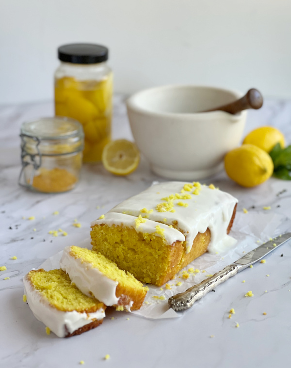 preserved lemon tea cake loaf with a jar of preserved lemons and a jar of turmeric.
