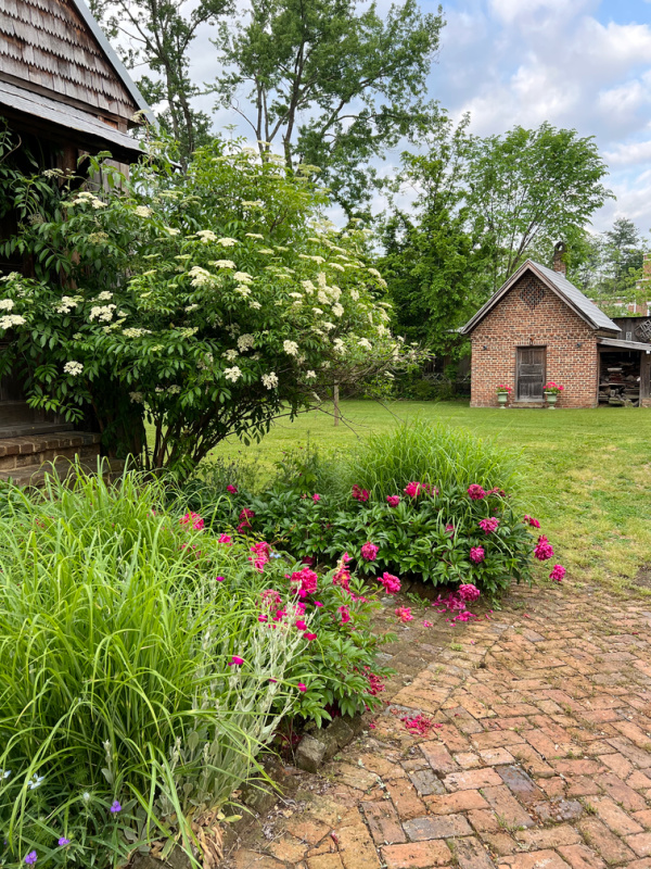 Small brick building with flowers, peonies and grasses.