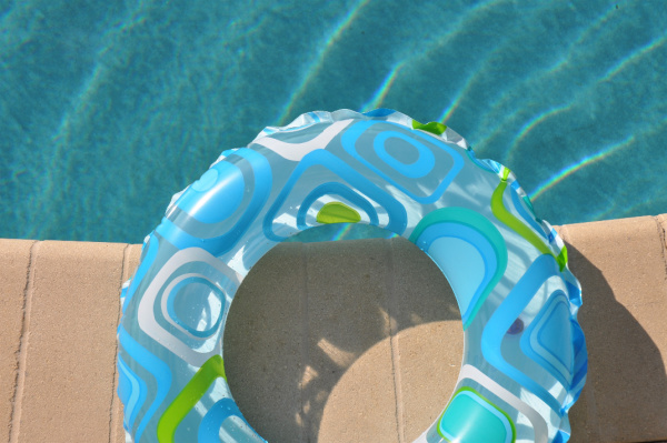 Blue and green ring pool float at the edge od a pool.