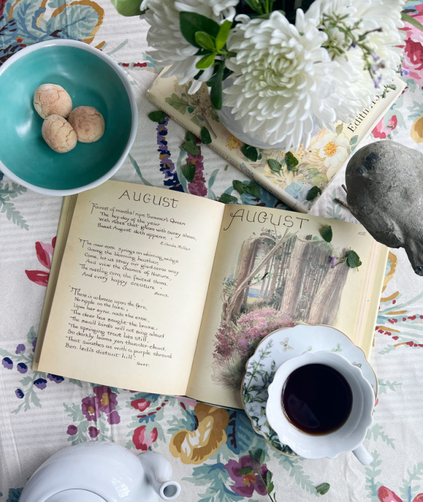 August flatlay with books, coffee, bird.