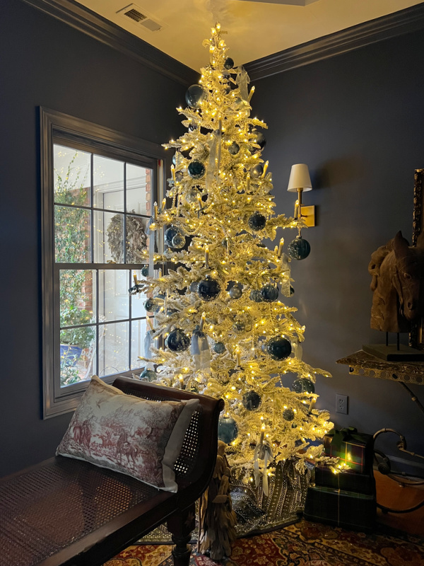 King of Christmas Noble Flocked Artificial Tree in a blue living room.