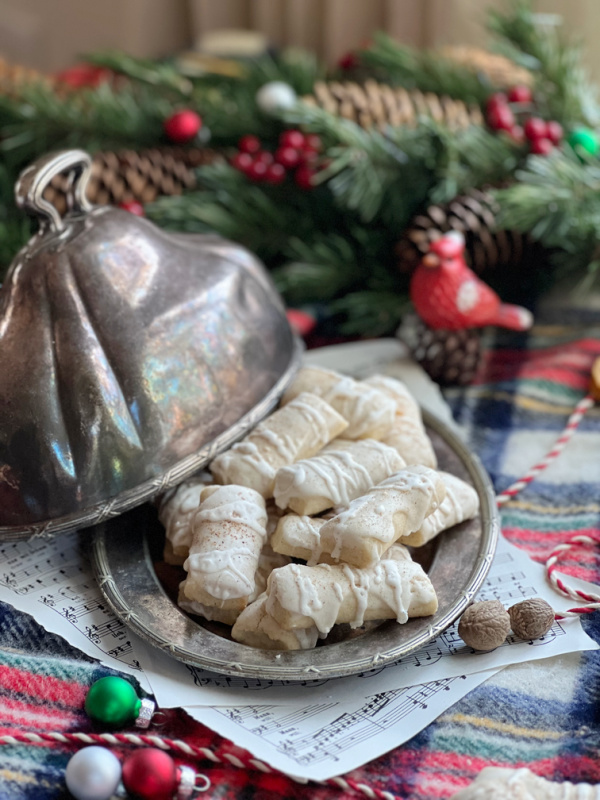 nutleg logs on a silver platter with lid and a cardinal with red, green, silver christmas ornaments.