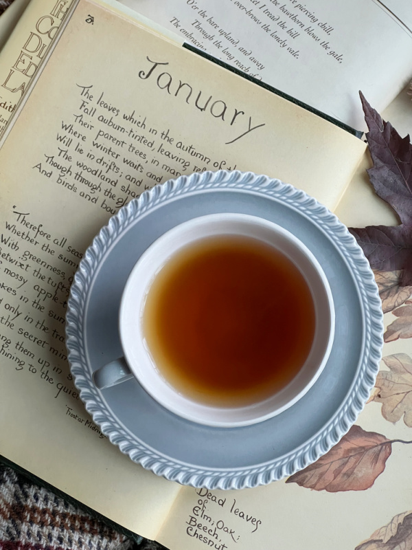 January flatlay with cup of tea and Country Diary of an Edwardian Lady Opened to January.