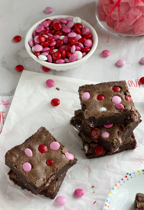 Valentine's M&M Fudge Brownies on two stacks with bowl of M&M candy.